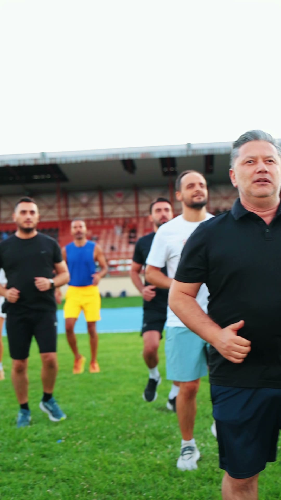 Koşucular çim sahada birlikte koşuyor